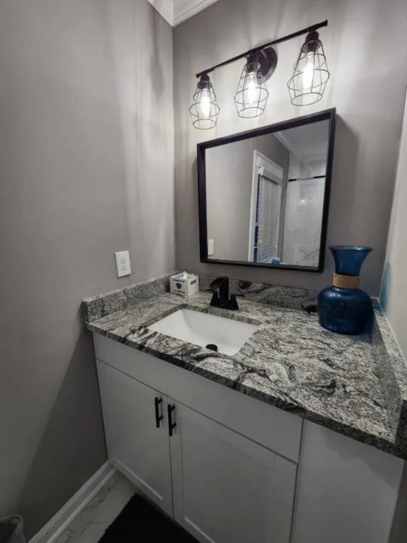Bathroom with baseboards, ornamental molding, vanity, and marble finish floor