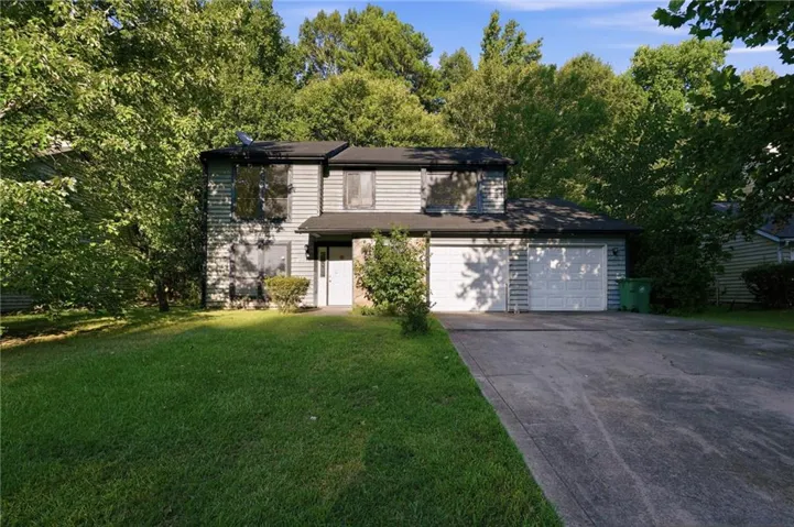 Two-story siding exterior with an attached two-car garage, concrete driveway, and front lawn