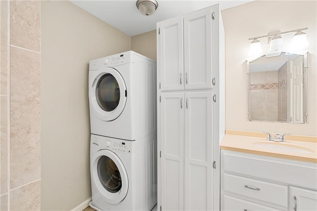 Laundry area featuring sink and stacked washing maching and dryer