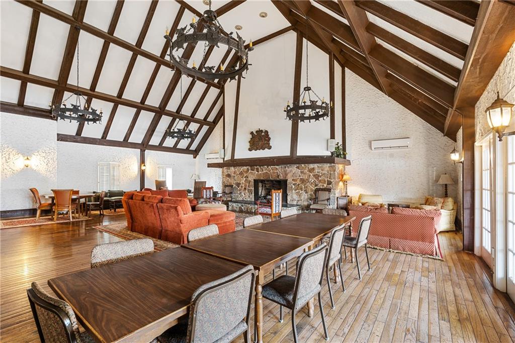 Dining area with high vaulted ceiling, a stone fireplace, and a notable chandelier