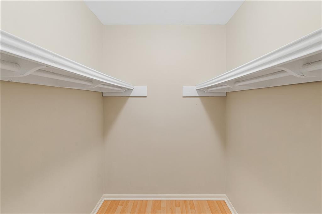 Walk in closet with hardwood / wood-style flooring