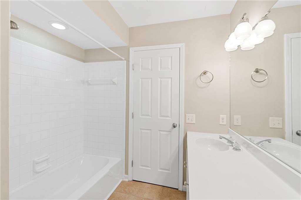 Bathroom with tiled shower / bath combo, tile floors, and vanity