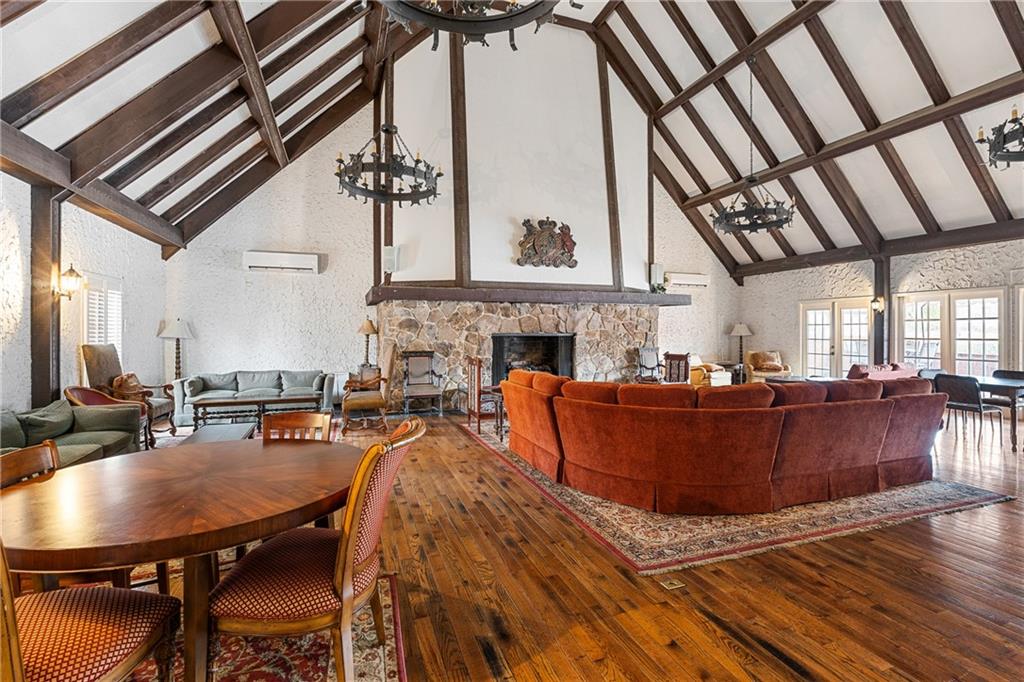 Dining room with wood-type flooring, an inviting chandelier, a fireplace, and high vaulted ceiling