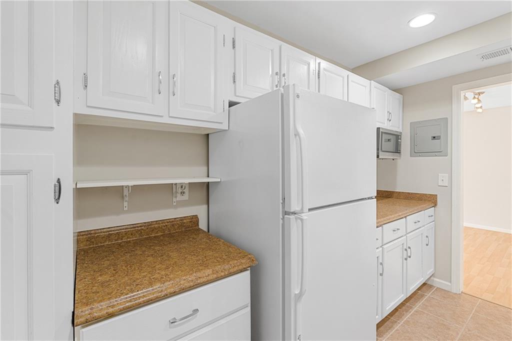 Kitchen with white cabinets, light tile floors, and white fridge