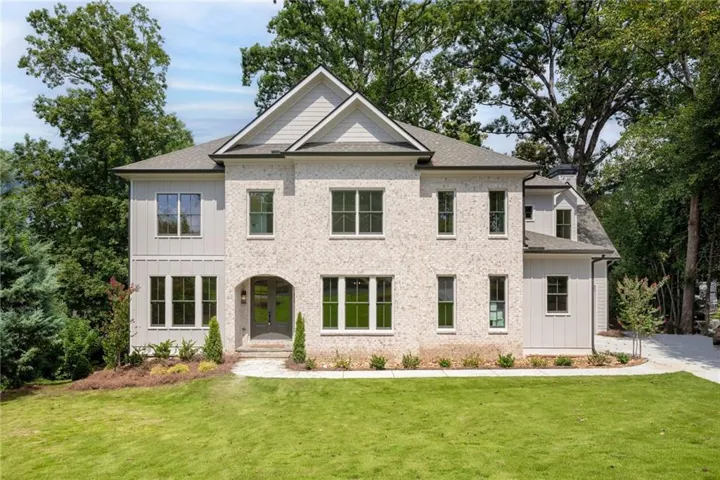 Exterior featuring a light brick facade, board and batten siding, multiple gables, an arched entryway, and dark-framed windows