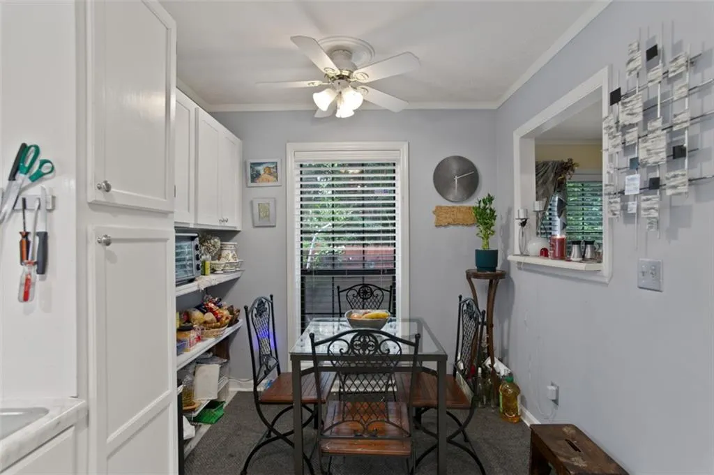 Dining space with ceiling fan, crown molding, and carpet flooring