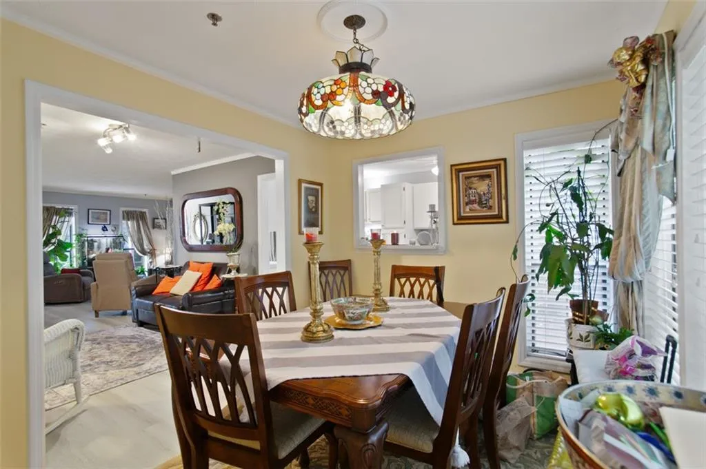 Dining room featuring healthy amount of natural light, ornamental molding, and wood finished floors
