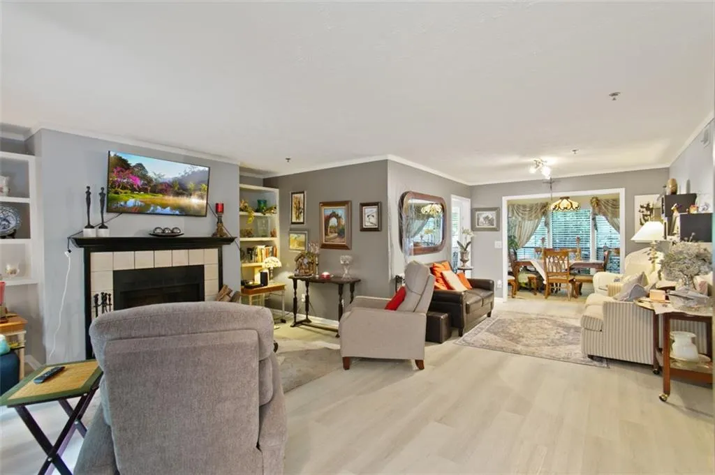Living area with ornamental molding, a chandelier, light wood-style flooring, and a fireplace