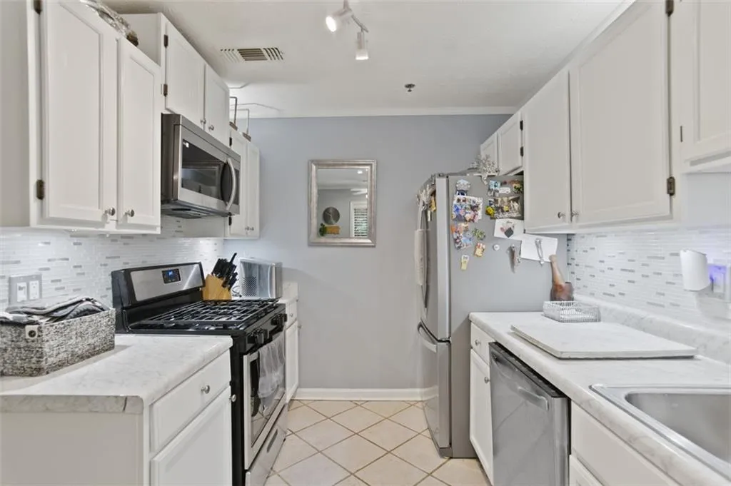 Kitchen with stainless steel appliances, light countertops, and white cabinetry