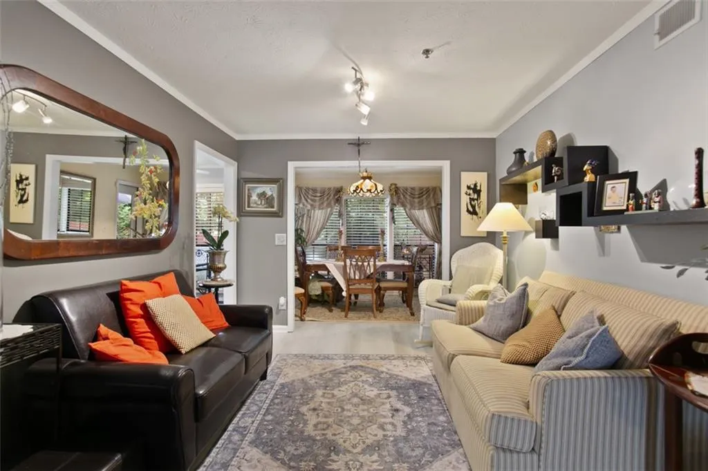 Living room featuring ornamental molding, wood finished floors, and a chandelier