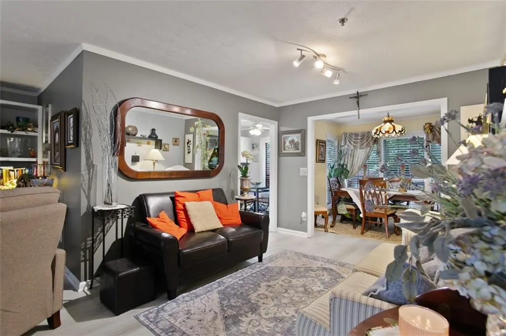 Living area featuring wood finished floors, crown molding, and a ceiling fan