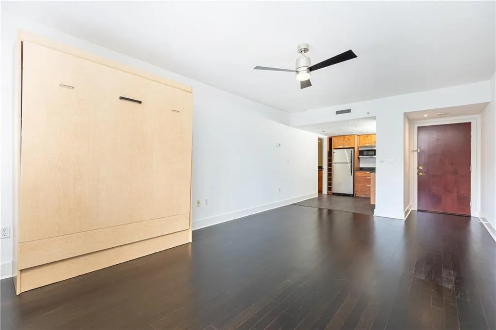 Unfurnished living room with dark wood-style flooring and ceiling fan