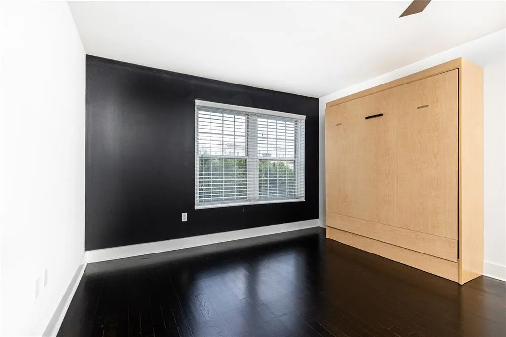 Empty room featuring dark wood-style floors and baseboards