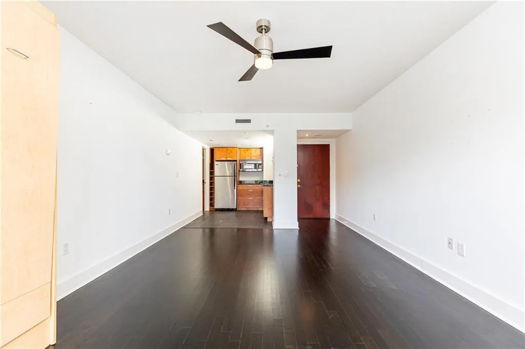 Unfurnished living room featuring dark wood-type flooring and ceiling fan