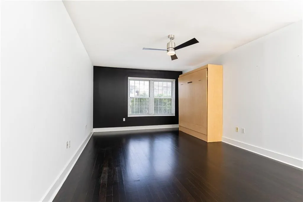 Unfurnished room with dark wood-style floors and a ceiling fan