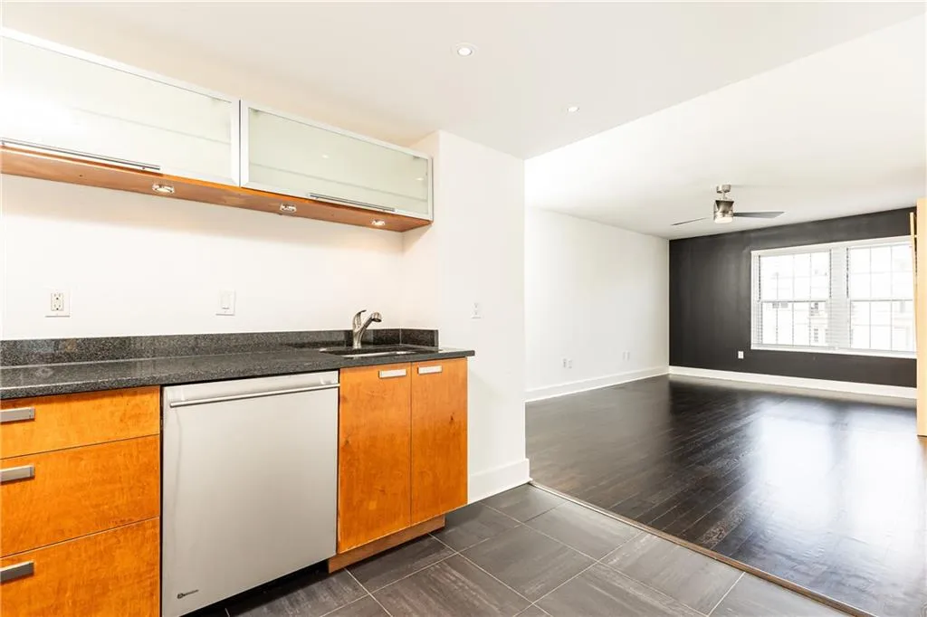 Kitchen with dishwashing machine, open floor plan, glass insert cabinets, a ceiling fan, and brown cabinetry