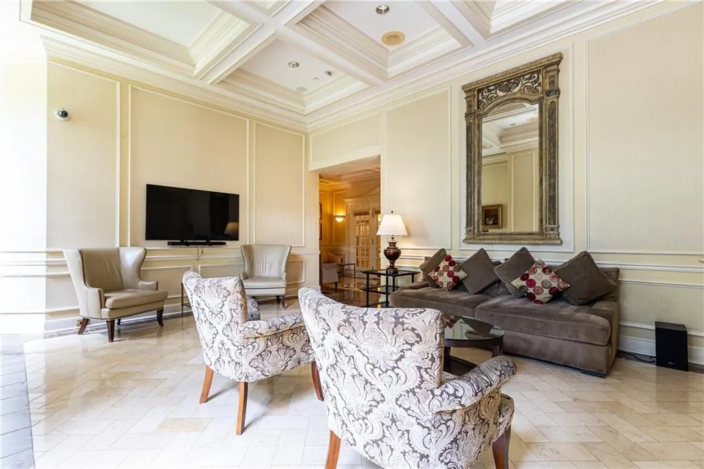 Living room with a decorative wall, beamed ceiling, ornamental molding, and coffered ceiling