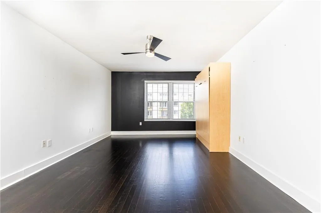 Spare room featuring dark wood-style flooring and a ceiling fan