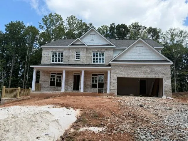 Two-story home with brick and shingle siding, a covered front porch with white columns, multiple gabled rooflines, and an integrated garage