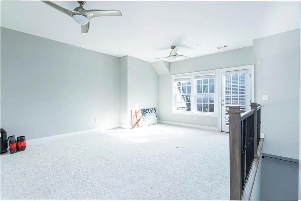 Carpeted empty room featuring a ceiling fan and lofted ceiling