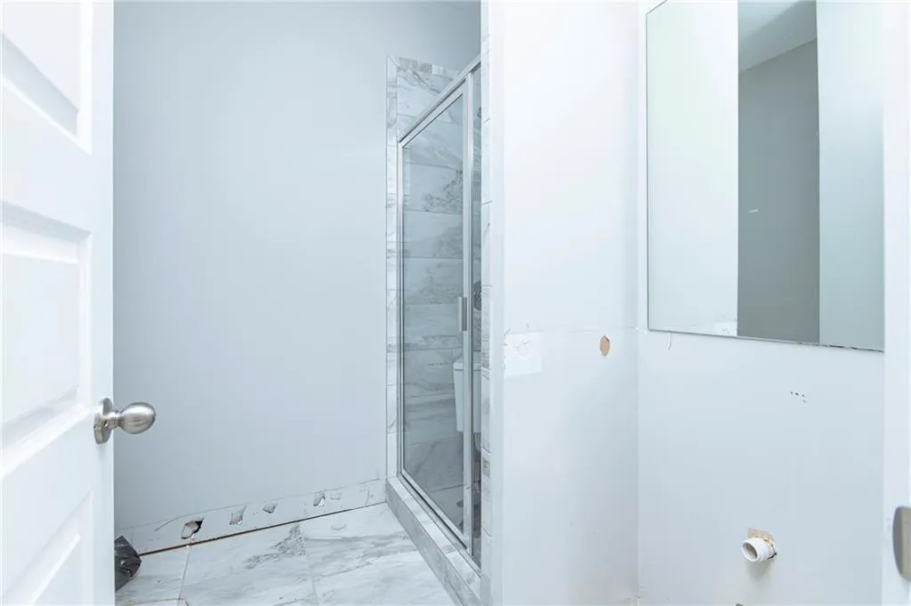 Bathroom featuring marble finish flooring and a shower stall
