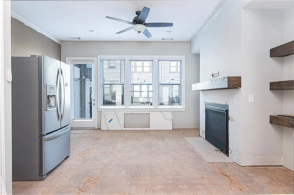 Kitchen featuring stainless steel fridge with ice dispenser, a fireplace with flush hearth, ceiling fan, and crown molding