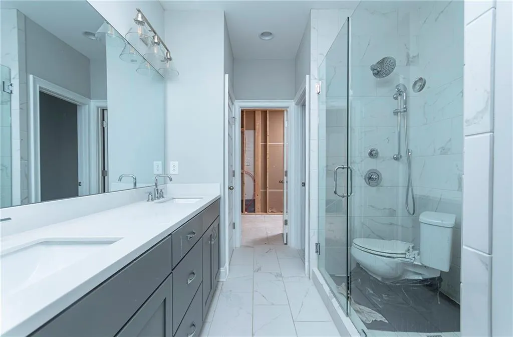 Full bathroom with double vanity, light marble finish flooring, and a marble finish shower