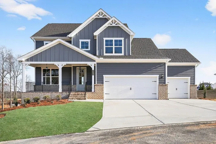 Craftsman house featuring brick siding, a porch, an attached garage, and board and batten siding