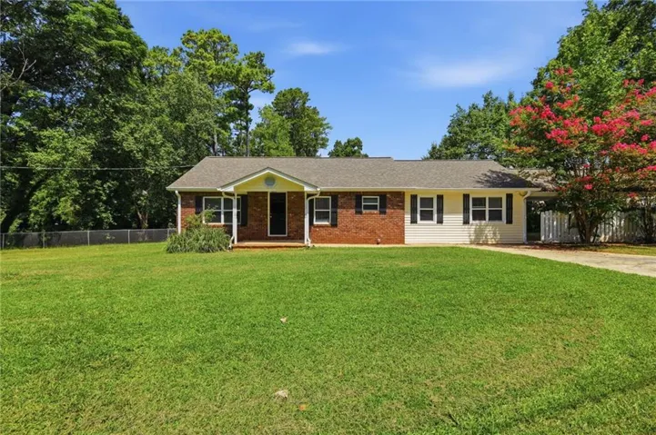 Brick and siding exterior, expansive front lawn, covered entry porch, dark shutters, and a paved driveway