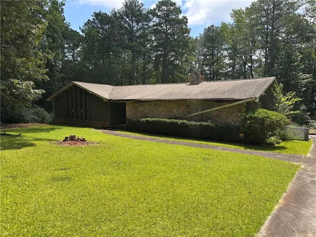 Spacious front lawn with a concrete pathway leading to the entrance