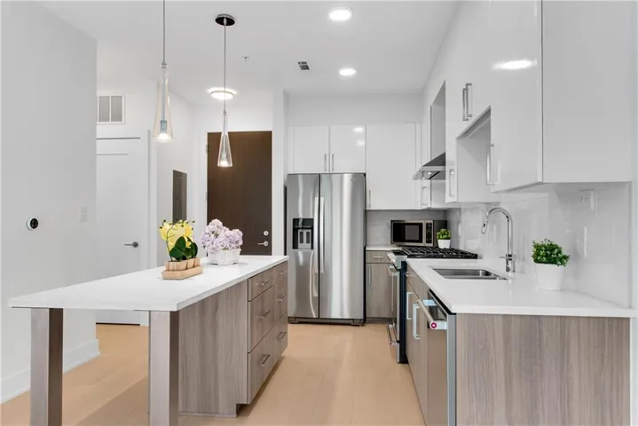 Kitchen featuring modern cabinets, white cabinets, a center island, stainless steel appliances, and backsplash