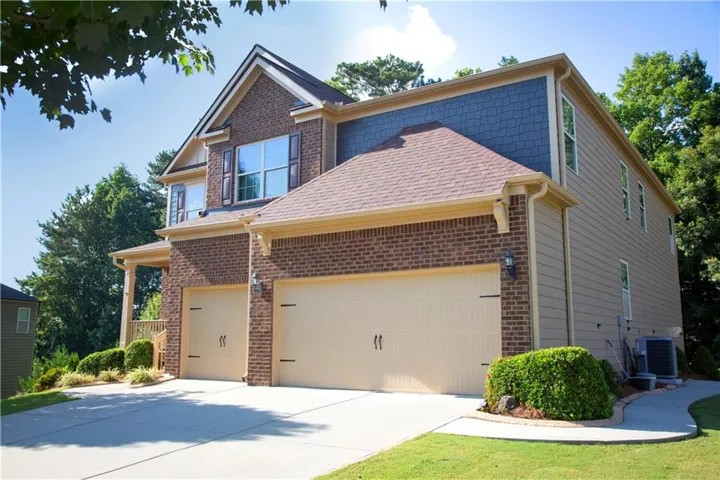 Brick and siding exterior with a two-car garage, concrete driveway, and a front porch