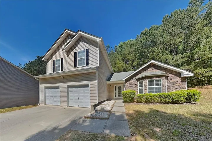 Two-story residence featuring a stone facade accent, dual garage doors, and a covered entry