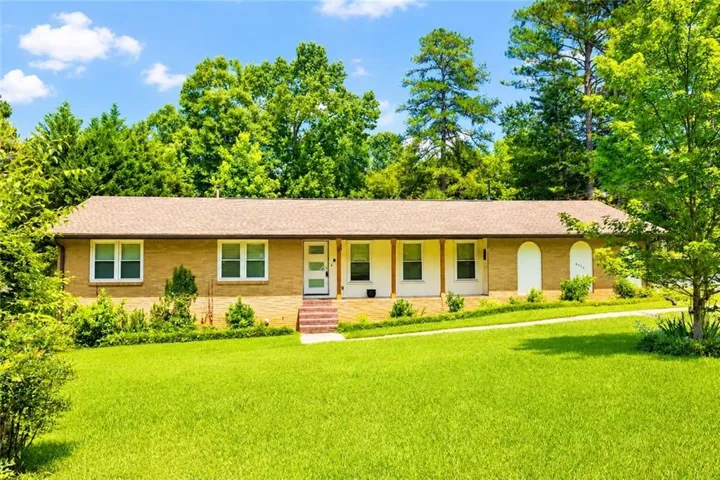 Ranch-style exterior with a light brown brick façade and a classic shingle roof