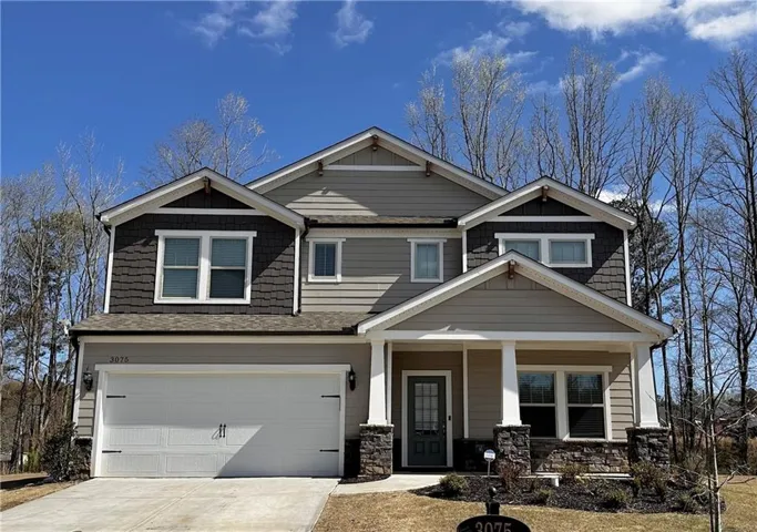 Two-story residence featuring a two-car garage, stone façade accents, a covered front porch, and horizontal siding