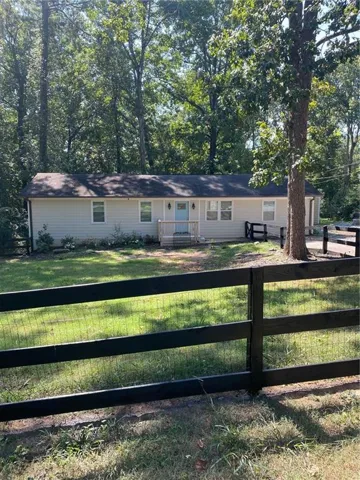 Single story home with a fenced front yard, a garage, and view of wooded area