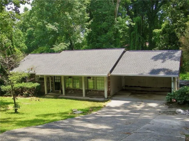 Ranch-style exterior featuring a carport, a dark entry door, and multiple front windows with light-colored frames