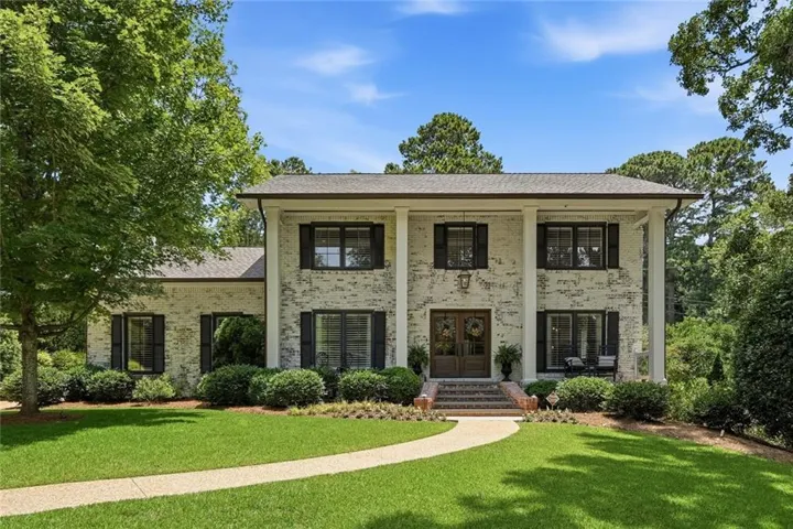 Two-story Colonial-style residence featuring a painted brick facade and prominent white columns