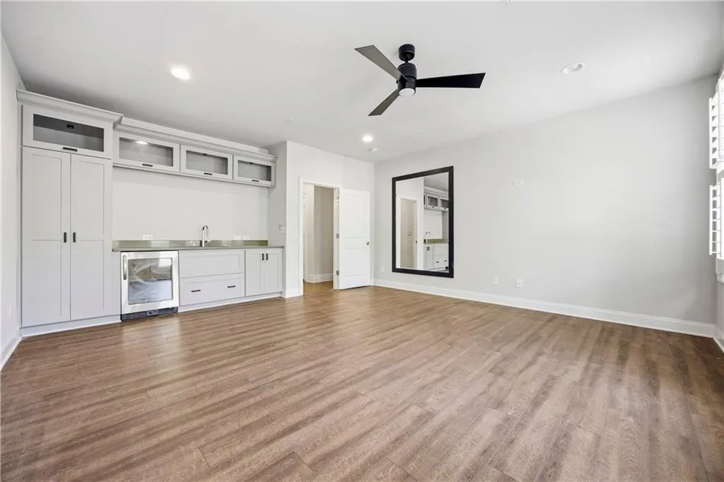 Unfurnished living room with wine cooler, wet bar, dark wood-style flooring, a ceiling fan, and recessed lighting
