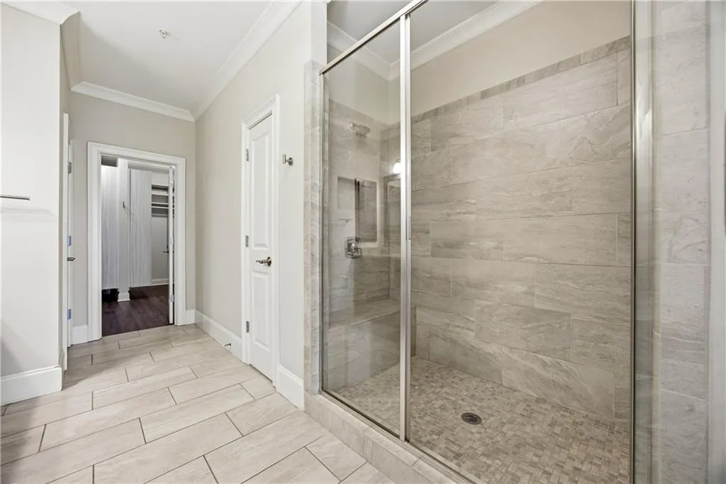 Bathroom featuring ornamental molding, a shower stall, and a walk in closet