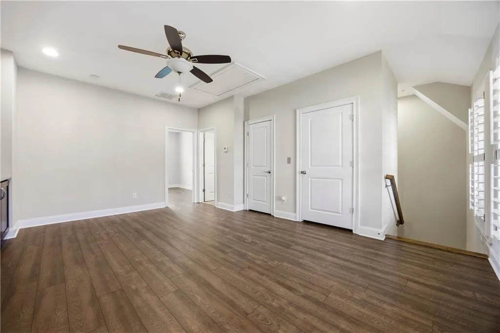 Unfurnished bedroom with a ceiling fan, dark wood-type flooring, and multiple closets