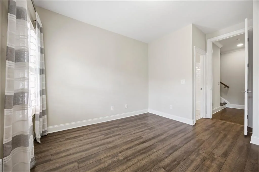 Unfurnished bedroom featuring dark wood-type flooring and ensuite bath