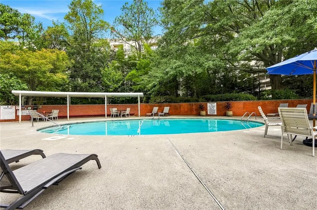 Resort-style pool with concrete decking, a covered patio area, and a surrounding brick wall