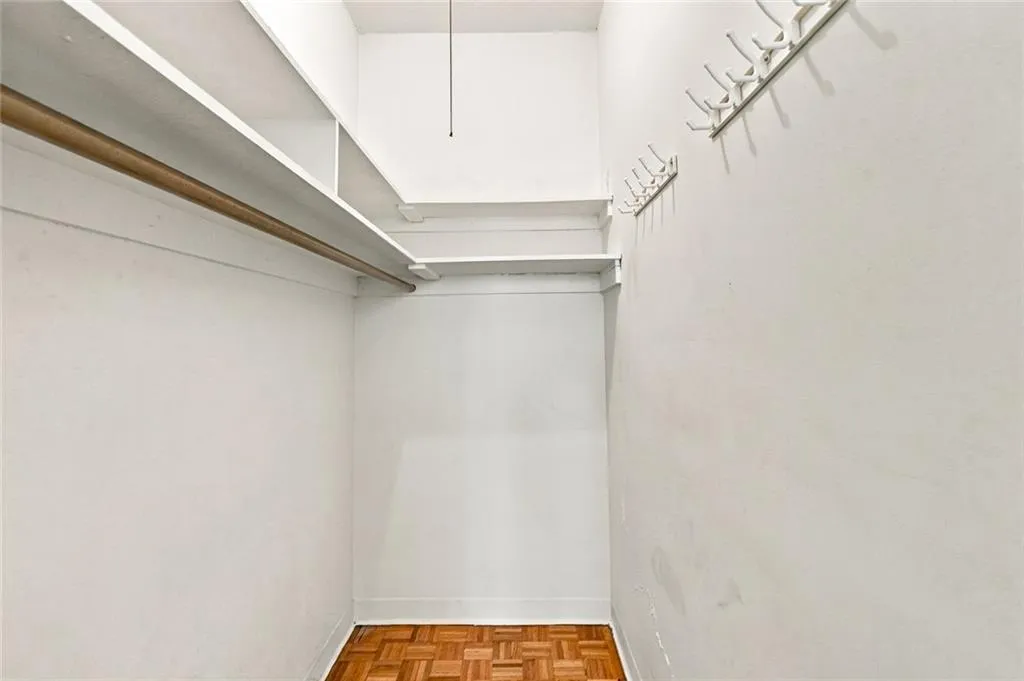 Closet with built-in shelving, a garment rod, and multiple wall-mounted hooks