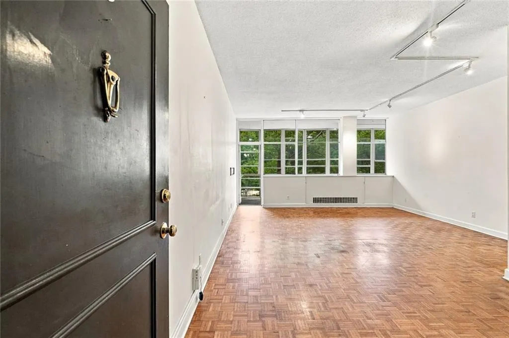 Parquet wood-finish flooring, full-height windows, track lighting, and a dark-paneled entry door