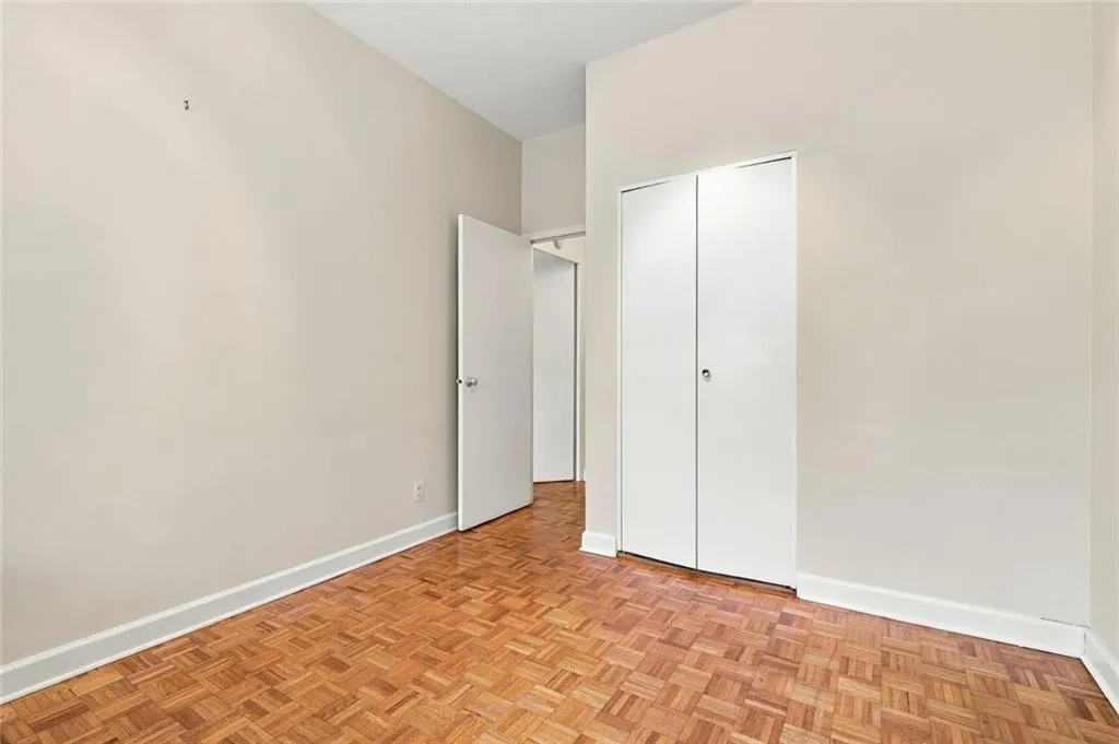 Parquet wood flooring, white walls, white trim, and a white bi-fold closet door