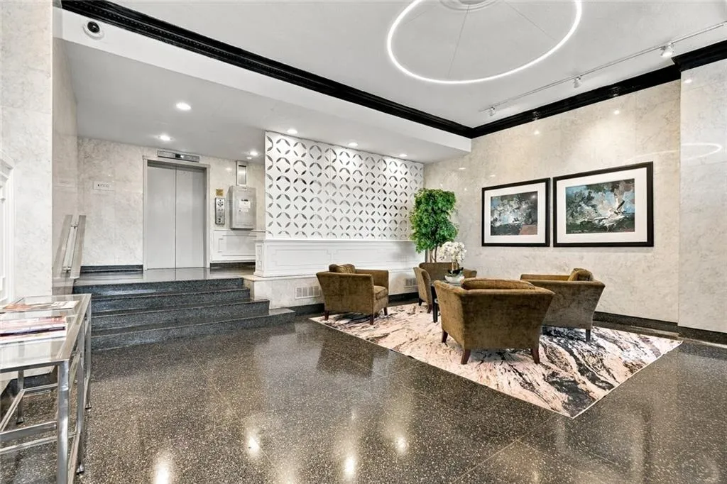 Polished terrazzo flooring, marble-look wall finishes, recessed lighting, elevator access, and a decorative screen partition