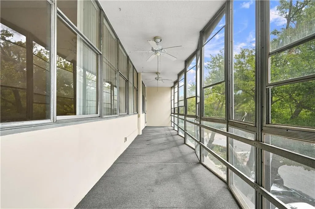 Enclosed balcony featuring extensive window panels, dual ceiling fans, and neutral wall tones