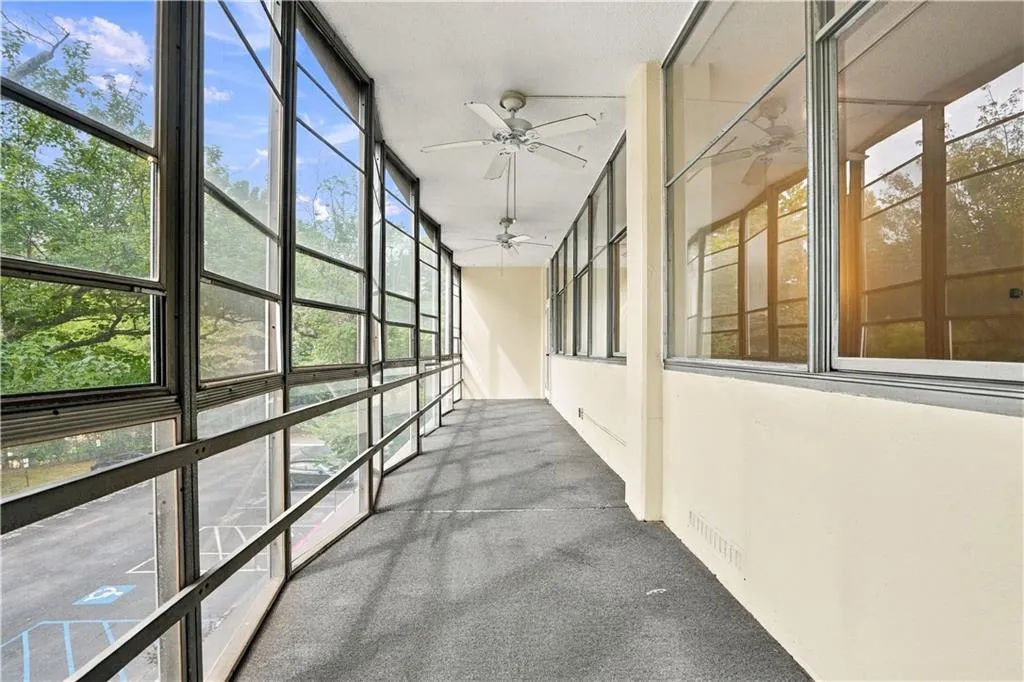 Enclosed sunroom featuring expansive windows, neutral carpeting, and multiple ceiling fans