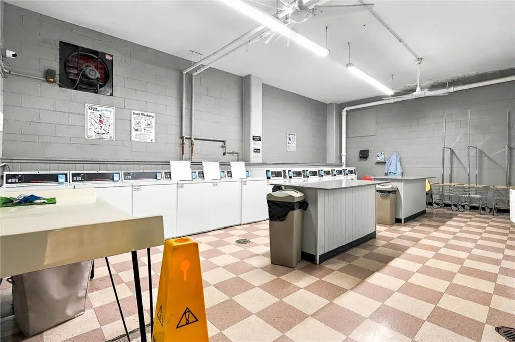 Dedicated laundry facility with multiple washing machines, block wall construction, and checkerboard floor tiles